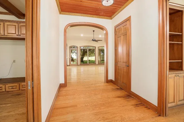 a view of a hallway with wooden floor and a bathroom