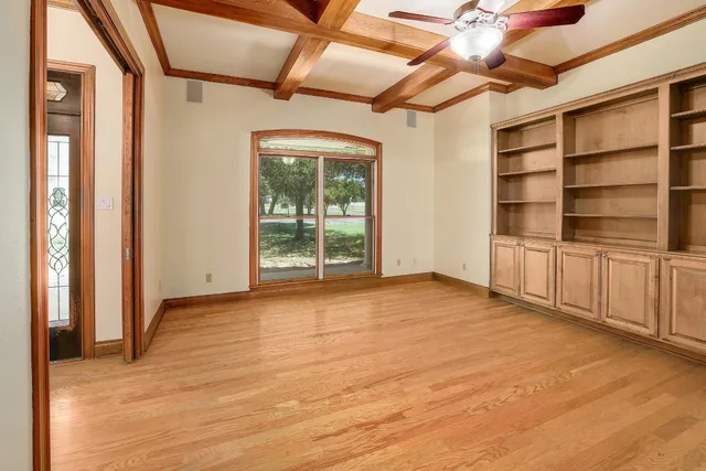 a view of an empty room with a window and wooden floor