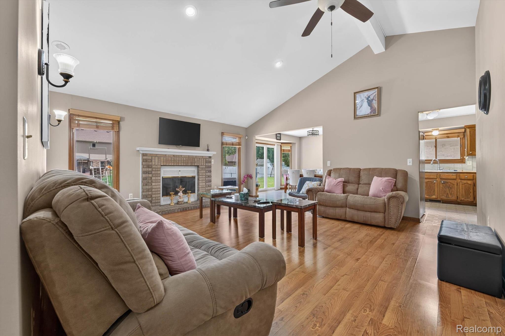 46362 Springhill Drive Utica, MI 48317 - Photo 6 of 59 Spacious living area featuring vaulted ceilings, wood-finish flooring, a brick fireplace with a white mantel, recessed lighting, and a ceiling fan