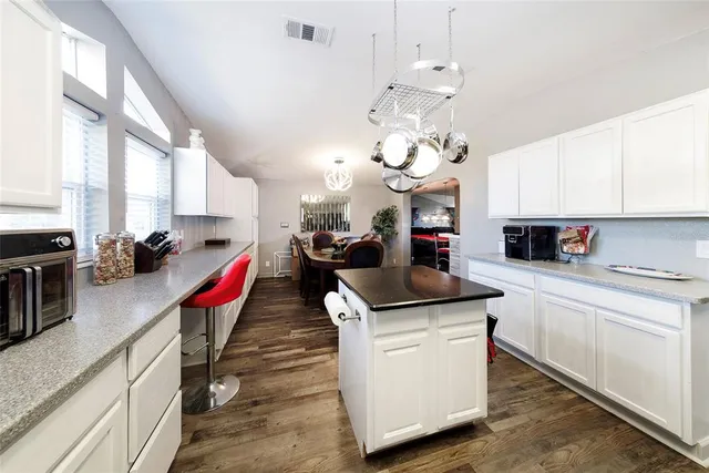 a kitchen that has a lot of cabinets and wooden floor