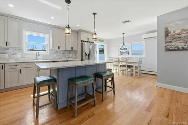 a kitchen with kitchen island granite countertop wooden floors and white cabinets