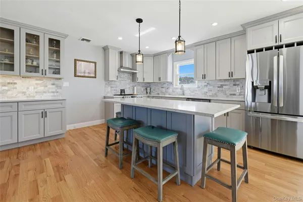a large kitchen with stainless steel appliances granite countertop a stove a sink dishwasher and a refrigerator with wooden floor