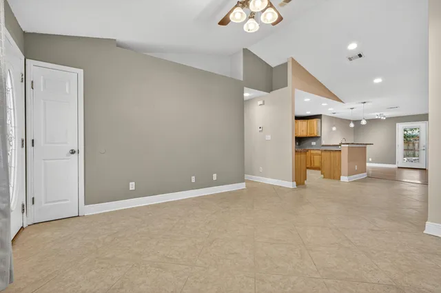 an empty room with a kitchen and a chandelier fan