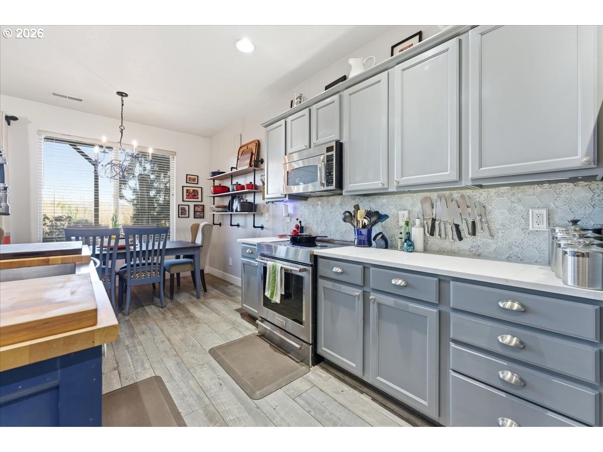 21601 Northeast Willow Glen Road Fairview, OR 97024 - Photo 3 of 48 a kitchen with stainless steel appliances kitchen island granite countertop a table chairs and a wooden cabinets