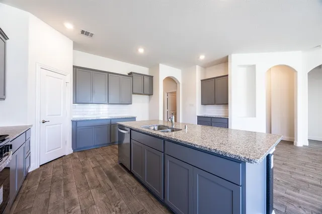 a kitchen with granite countertop kitchen island a sink appliances and a counter space