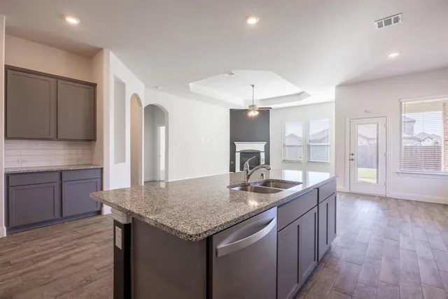 a kitchen with granite countertop kitchen island stainless steel appliances a sink and a refrigerator