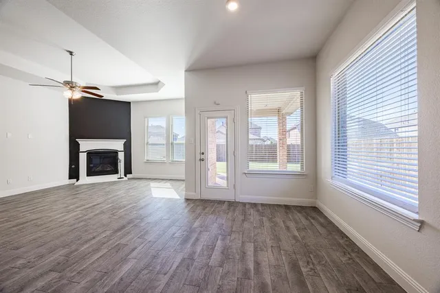a view of an empty room with wooden floor fireplace and a window