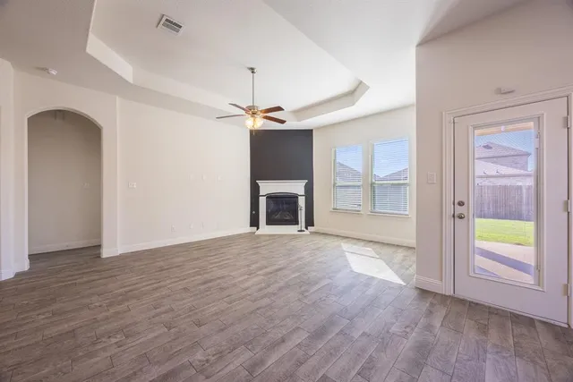 an empty room with wooden floor a ceiling fan and windows