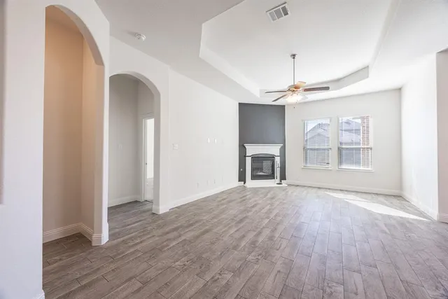 an empty room with wooden floor a ceiling fan and windows