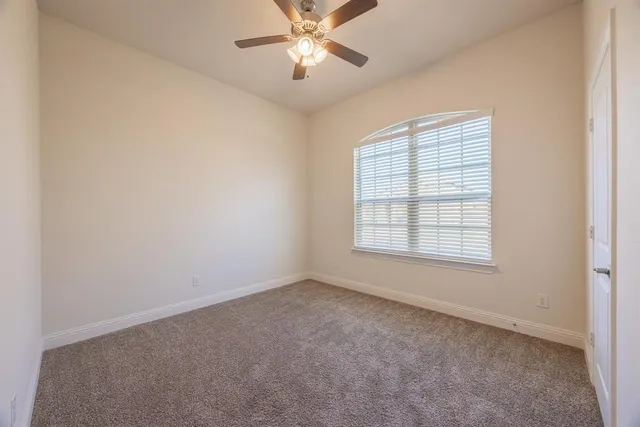an empty room with windows and fan