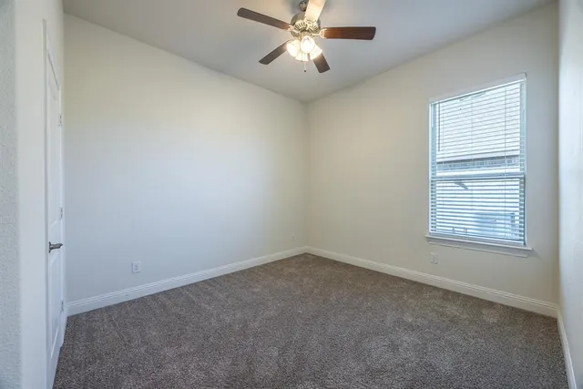 an empty room with a window and a fan