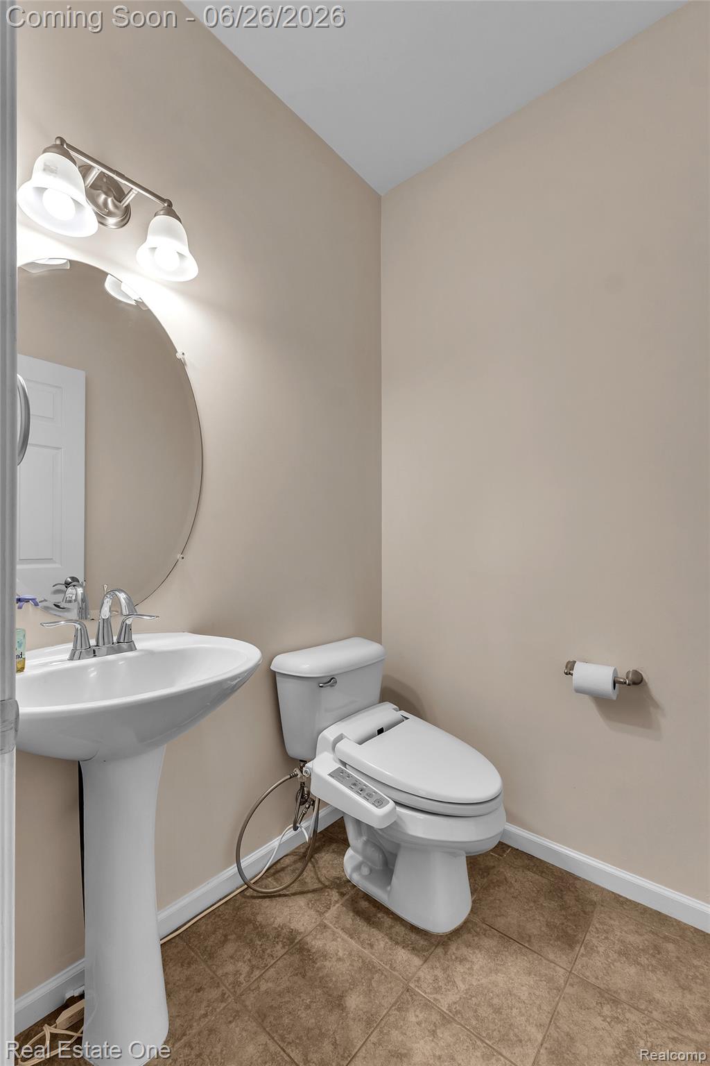 41590 Mitchell Road Novi, MI 48377 - Photo 20 of 45 Pedestal sink with chrome faucet, circular wall mirror, and a three-light vanity fixture