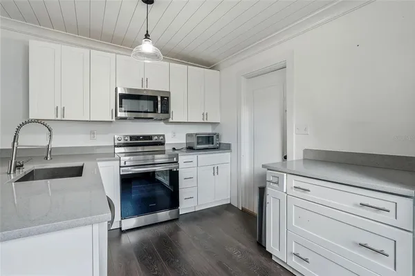 a kitchen with granite countertop a sink stainless steel appliances and white cabinets