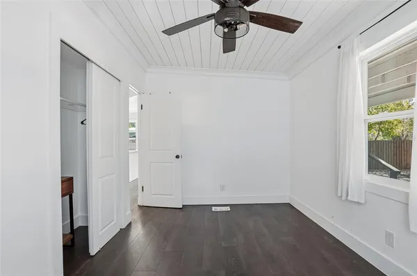 an empty room with wooden floor fan and windows