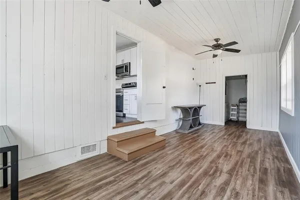 an empty room with wooden floor ceiling fan and windows