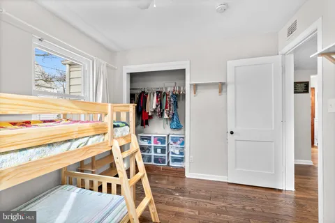 a view of a bedroom with wooden floor & lounge chair