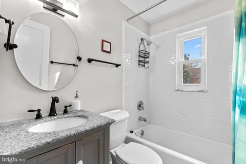a bathroom with a granite countertop sink mirror toilet and a bathtub