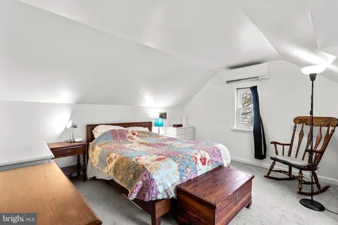 a bedroom with a bed a chair and the dresser