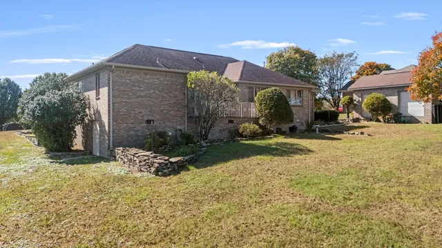 a front view of a house with yard and covered with trees