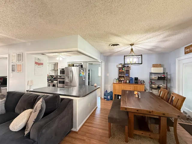 a living room with furniture kitchen view and a wooden floor