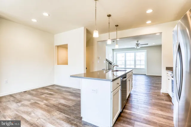 a kitchen with stainless steel appliances granite countertop a refrigerator a sink dishwasher a stove and a refrigerator with wooden floor