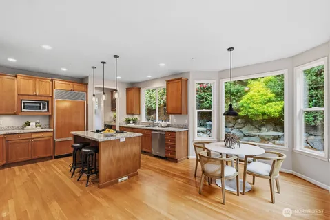 a kitchen with kitchen island granite countertop a stove a sink a dining table and chairs with wooden floor