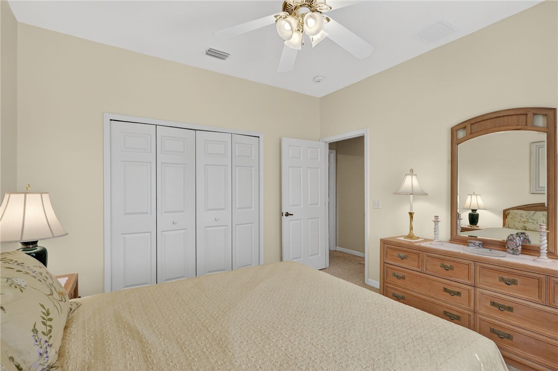 3075 73rd Place Vero Beach, FL 32967 - Photo 13 of 30 a bedroom with a bed and a chandelier