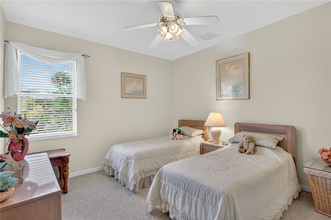 3075 73rd Place Vero Beach, FL 32967 - Photo 16 of 30 a bedroom with two beds and a chandelier