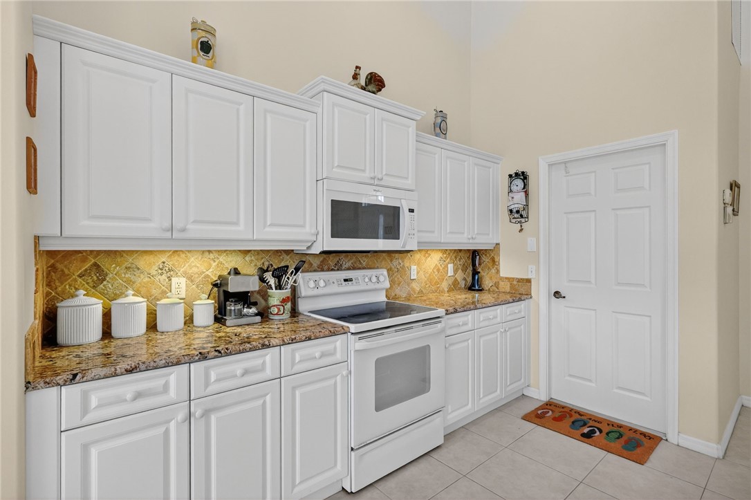 3075 73rd Place Vero Beach, FL 32967 - Photo 6 of 30 a kitchen with granite countertop white cabinets and white appliances