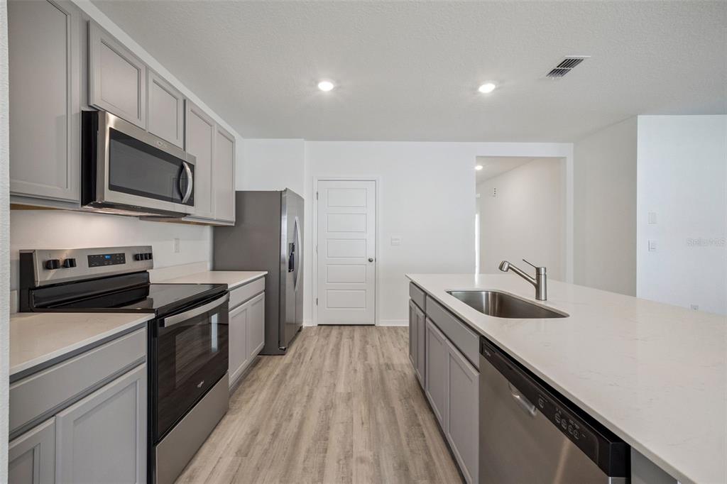 3515 Nettle Loop Tavares, FL 32778 - Photo 11 of 58 a kitchen with stainless steel appliances granite countertop a sink a stove top oven and wooden floors