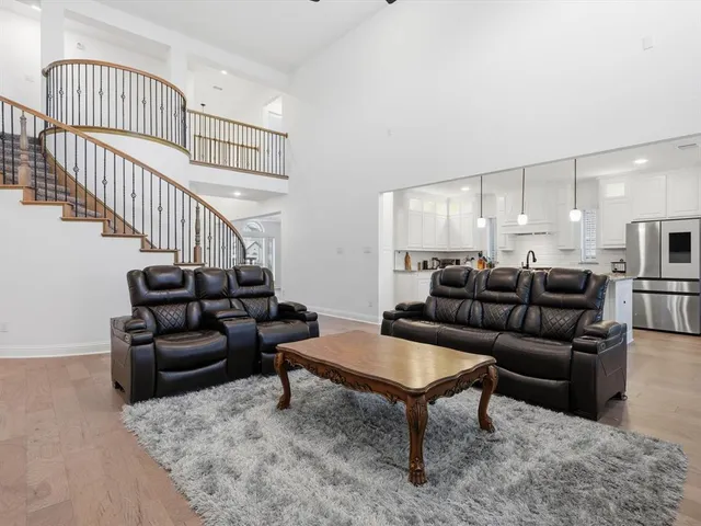 a living room with furniture and a dining table with wooden floor