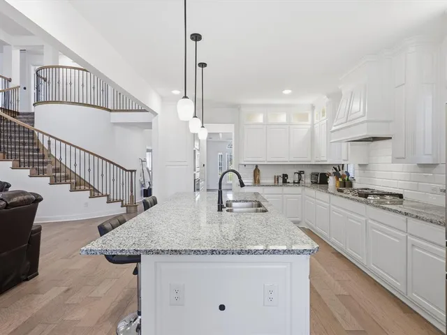 a kitchen with stainless steel appliances granite countertop a sink a stove and a wooden floor