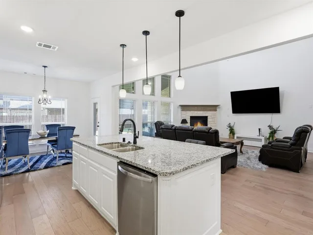a kitchen with a sink a counter top space and living room view
