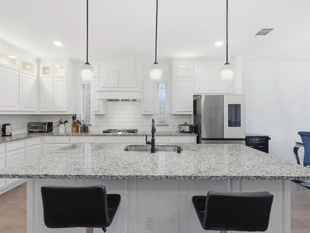 a kitchen with stainless steel appliances granite countertop a sink a microwave a refrigerator and a stove