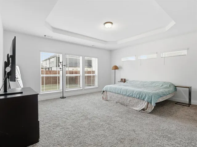 a spacious bedroom with a bed and a flat tv screen