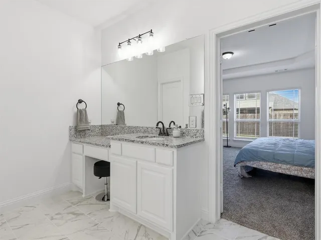 a en suite bathroom with a granite countertop sink and a mirror