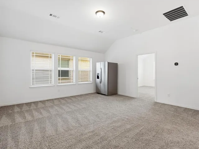 an empty room with windows and refrigerator