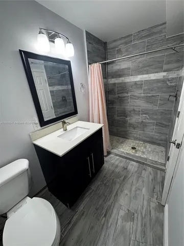 a bathroom with a sink vanity granite toilet and a mirror