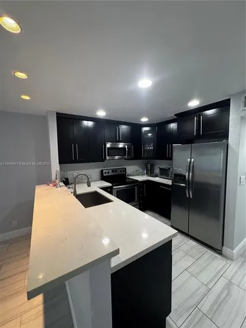 a kitchen with a sink a counter top space stainless steel appliances and cabinets