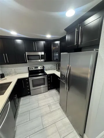 a kitchen with granite countertop a refrigerator and a sink