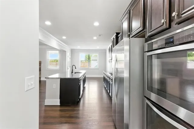 a kitchen with stainless steel appliances granite countertop a refrigerator a stove and a sink with wooden floor