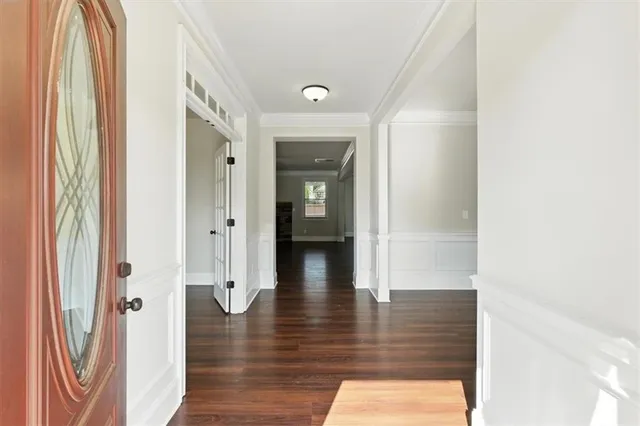 a view of a hallway with wooden floor and a bathroom