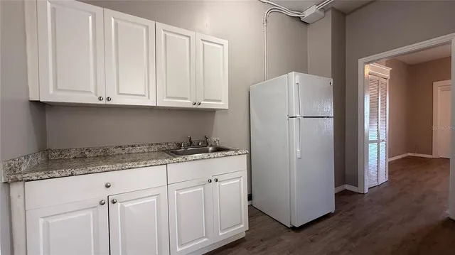 a kitchen with granite countertop a refrigerator sink and cabinets
