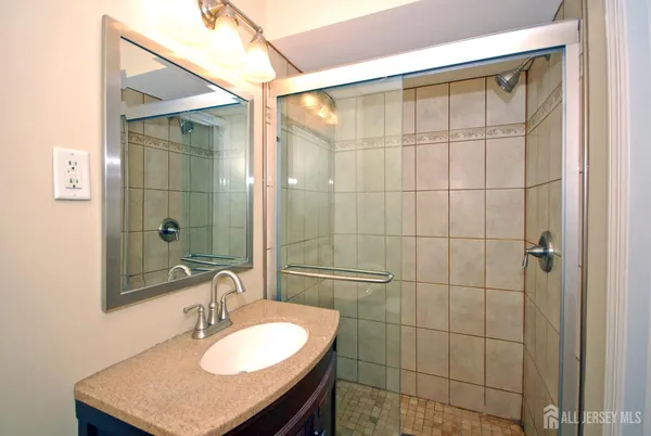 a bathroom with a sink vanity granite shower and a mirror