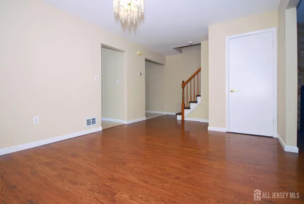 a view of an empty room with wooden floor and staircase