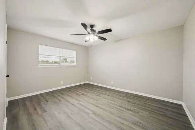 an empty room with wooden floor and ceiling fan