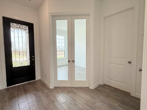 a view of an empty room with wooden floor and closet