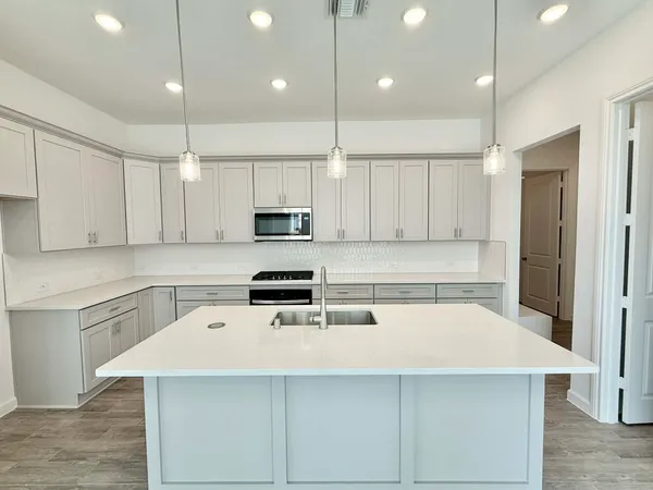 a kitchen with stainless steel appliances granite countertop a sink a stove and a refrigerator