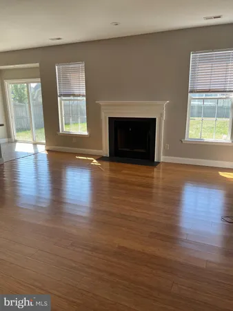 an empty room with wooden floor fireplace and windows
