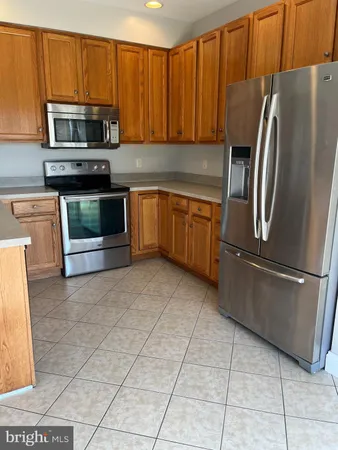 a kitchen with granite countertop a refrigerator and a stove top oven